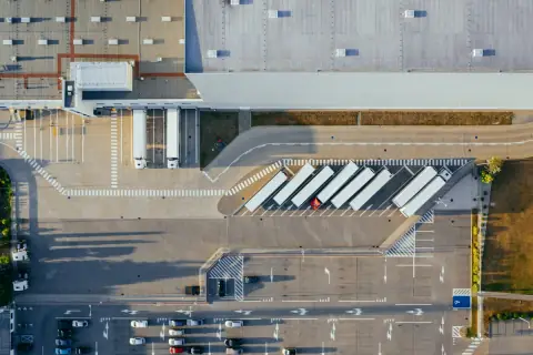 Overhead view of a logistics warehouse yard with lorry trailers parked in angled bays