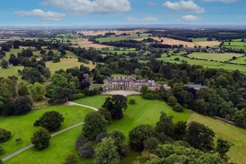 Aerial view of a country house in parkland with farmland stretching to the horizon