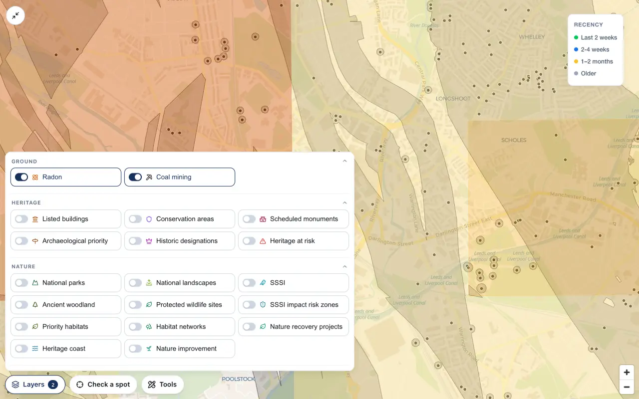 The Layers panel open over a map of Wigan with the new Ground section at the top, Radon and Coal mining both switched on. Behind the panel the coal mining development high risk area is drawn in grey bands across the town, over the pale radon squares.